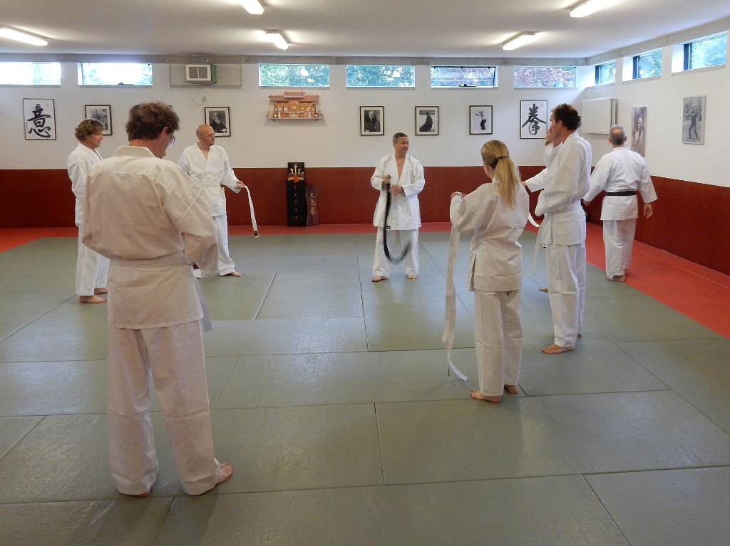 DSCN1695.JPG - De introductie begint met iedereen in een heus karatepak. En ja, zoals het hoort knoopt iedereen  zelf de band op de enig juiste wijze. Dat onder toeziend oog van sensei Rob en sensei Bert.